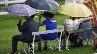 Racegoers shelter from the rain at Epsom